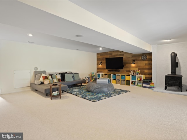 living area with a wood stove, wooden walls, visible vents, and carpet floors