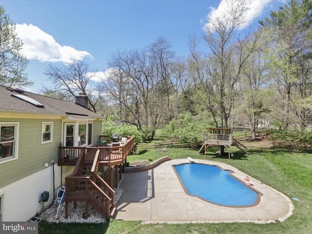 pool with a wooden deck, a yard, a patio area, fence, and a playground