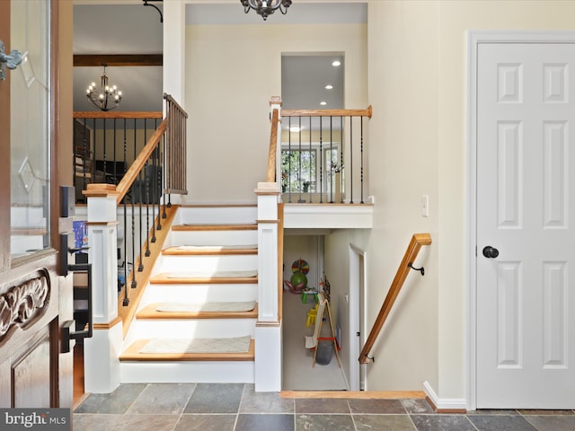 staircase featuring stone tile floors, an inviting chandelier, and baseboards