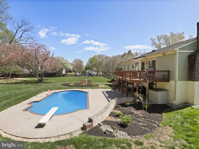 pool featuring a diving board, a yard, fence, a patio, and a wooden deck