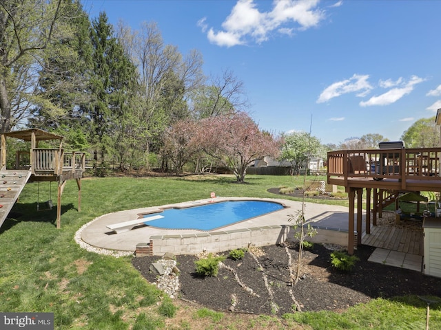 pool with a patio, a deck, a diving board, and a lawn