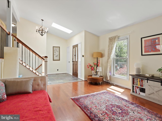 entrance foyer featuring vaulted ceiling with skylight, baseboards, a chandelier, wood finished floors, and stairs