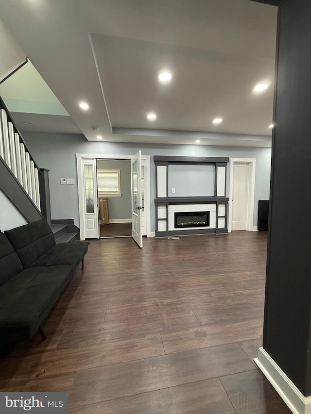 living area featuring stairs, a glass covered fireplace, baseboards, dark wood-style flooring, and recessed lighting