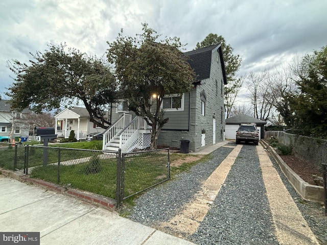 bungalow-style home with roof with shingles, a fenced front yard, driveway, stone siding, and a front yard