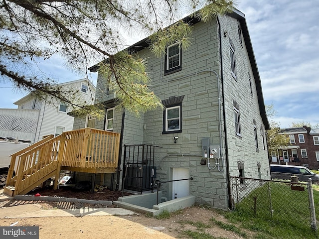rear view of house featuring fence and stone siding