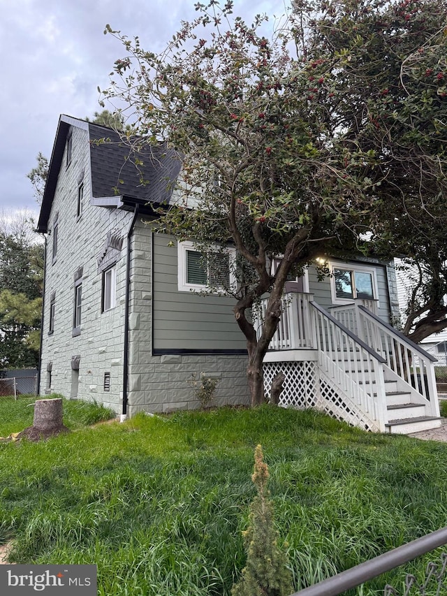 view of home's exterior with a yard and a shingled roof
