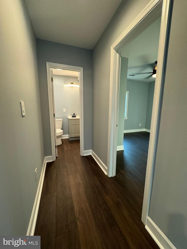 hall featuring baseboards and dark wood-style flooring