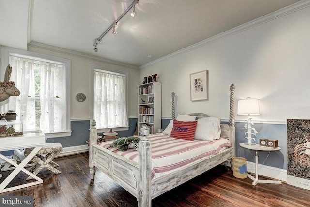 bedroom featuring track lighting, baseboards, wood finished floors, and crown molding