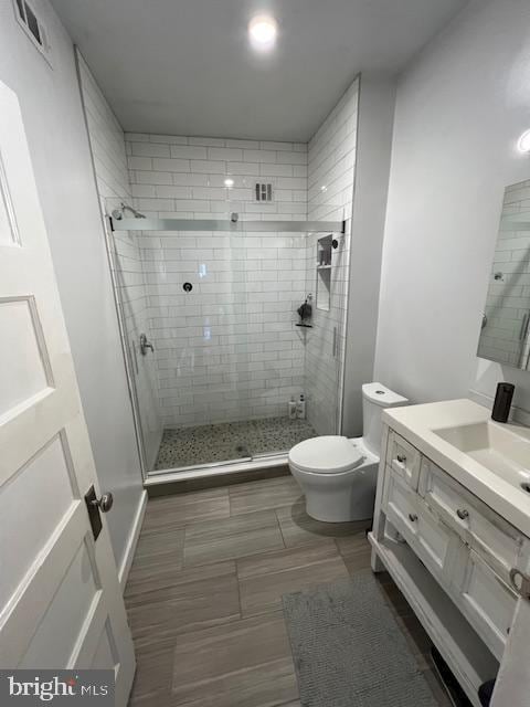 bathroom featuring a shower stall, toilet, and vanity