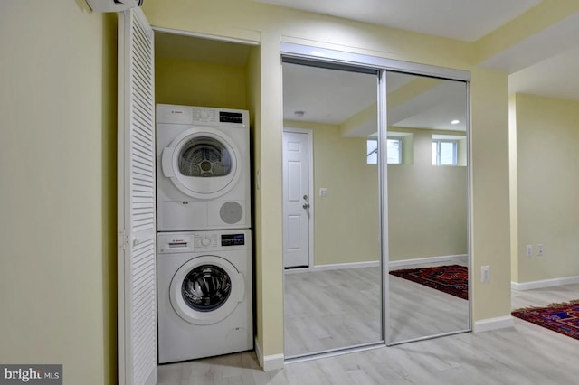laundry room featuring stacked washer / dryer, wood finished floors, and baseboards
