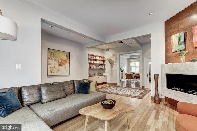 living area featuring wood finished floors, recessed lighting, a fireplace, and baseboards
