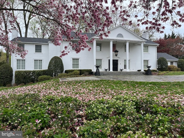 greek revival inspired property featuring a chimney and a front yard