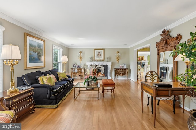 living area with crown molding, light wood finished floors, a lit fireplace, and baseboards