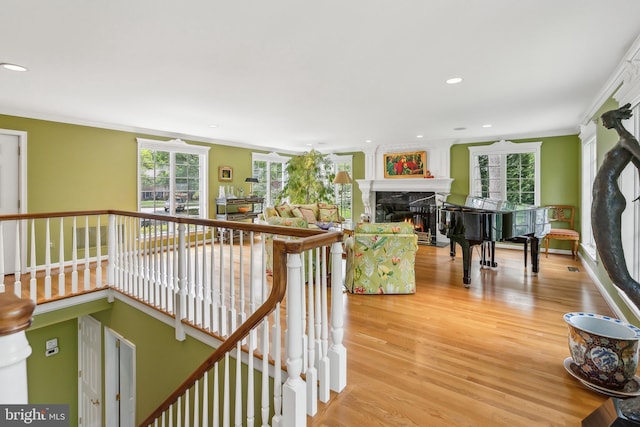 interior space with ornamental molding, recessed lighting, light wood-style flooring, and a lit fireplace
