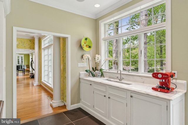 bar with a sink, crown molding, tile patterned flooring, and decorative columns
