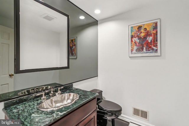 half bathroom with toilet, visible vents, vanity, and recessed lighting