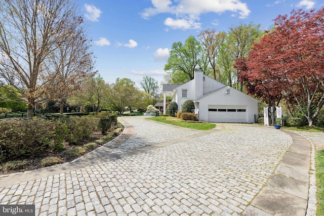 view of side of property featuring stucco siding, decorative driveway, and a chimney