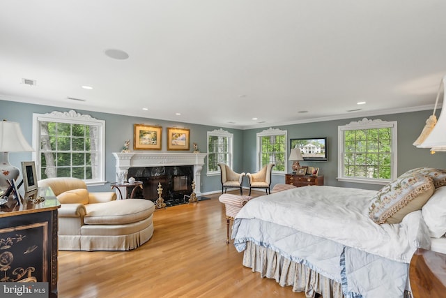 bedroom featuring wood finished floors, visible vents, crown molding, and multiple windows