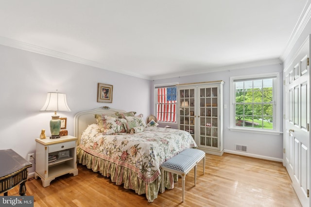 bedroom featuring crown molding, visible vents, wood finished floors, and baseboards
