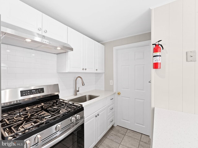 kitchen with stainless steel range with gas stovetop, a sink, backsplash, light countertops, and under cabinet range hood