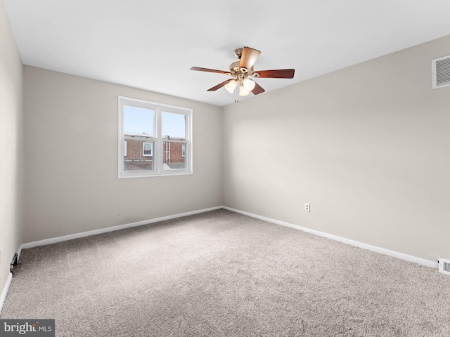 spare room with carpet floors, a ceiling fan, and baseboards