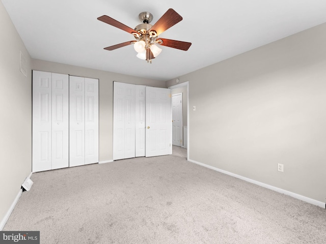 unfurnished bedroom featuring baseboards, a ceiling fan, carpet flooring, and two closets