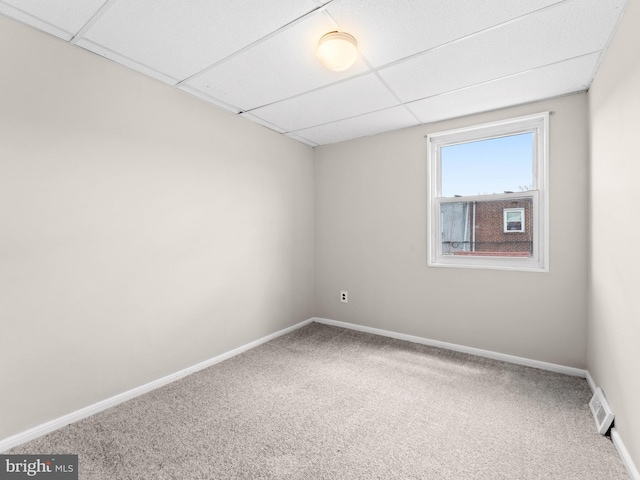 empty room with carpet floors, visible vents, and a paneled ceiling