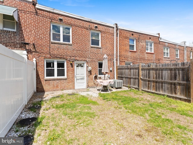 rear view of property featuring a fenced backyard, brick siding, and central air condition unit