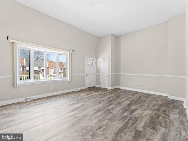 spare room with baseboards, wood finished floors, and visible vents