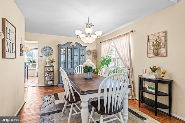 dining space featuring baseboards, an inviting chandelier, and wood finished floors