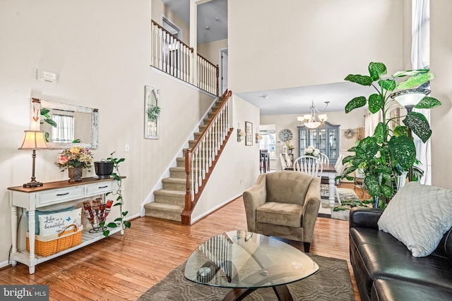 living room featuring a chandelier, wood finished floors, a high ceiling, and stairway