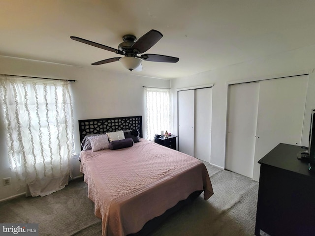 carpeted bedroom featuring multiple closets and a ceiling fan