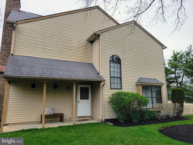 view of front of home featuring a shingled roof, a chimney, and a front lawn