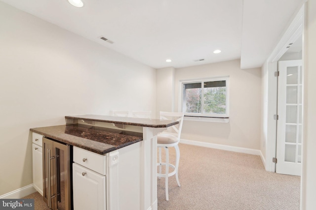 264 Capote Ct E, Severna Park, MD 21146 - kitchen featuring wine cooler, light colored carpet, a peninsula, baseboards, and a kitchen breakfast bar