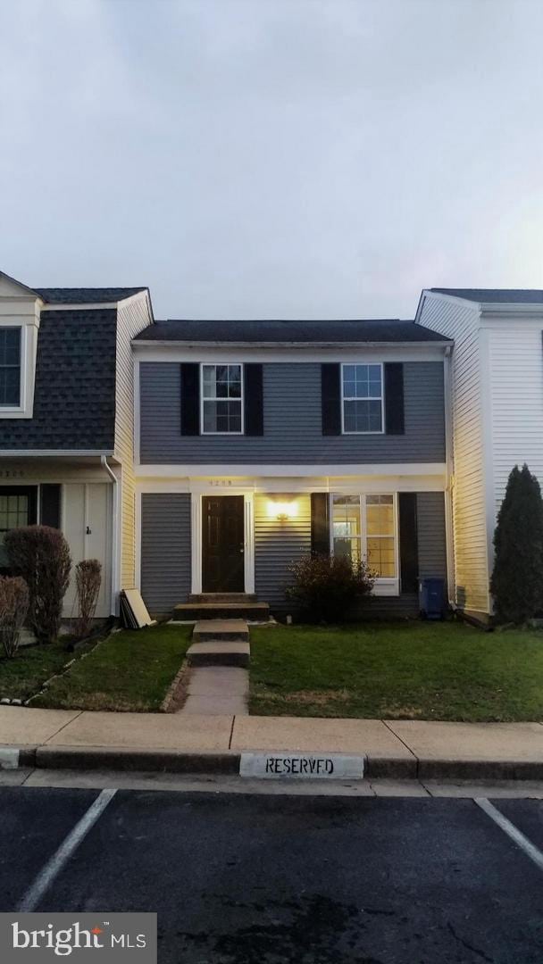 view of front of property with a front lawn, uncovered parking, and a shingled roof