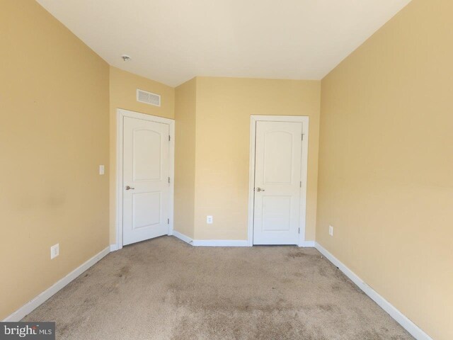 unfurnished bedroom with baseboards, carpet floors, and visible vents