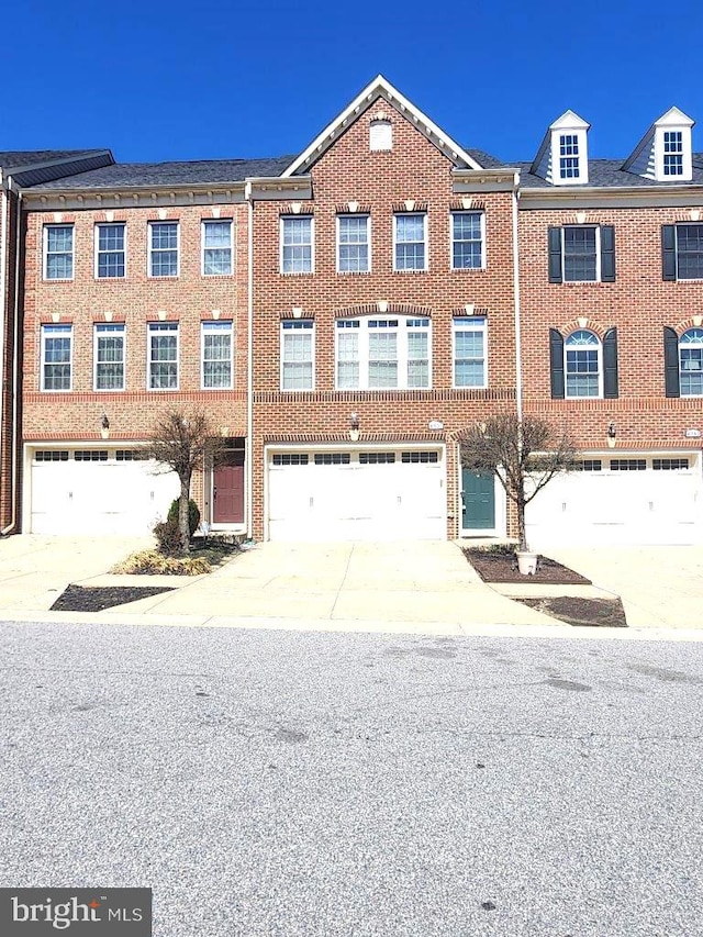 view of property featuring driveway, an attached garage, and brick siding
