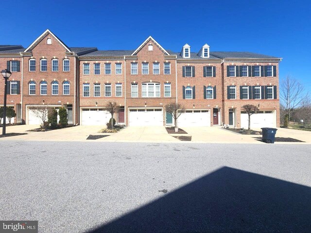 view of front facade featuring brick siding, driveway, and a garage