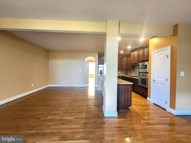 kitchen with dark brown cabinetry, light countertops, wood finished floors, and stainless steel appliances