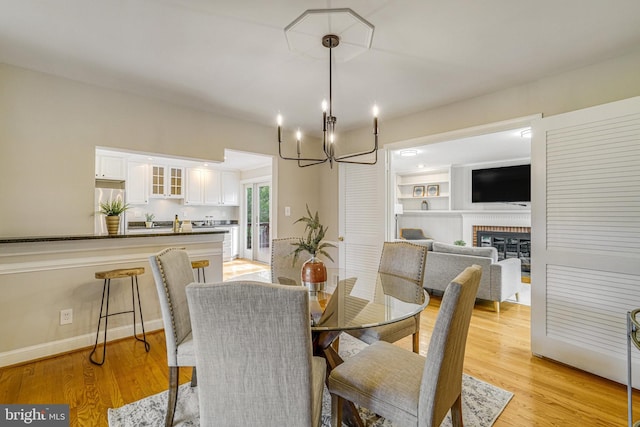 6515 Walters Woods Dr, Falls Church, VA 22044 - dining room with a fireplace, light wood-type flooring, and a notable chandelier