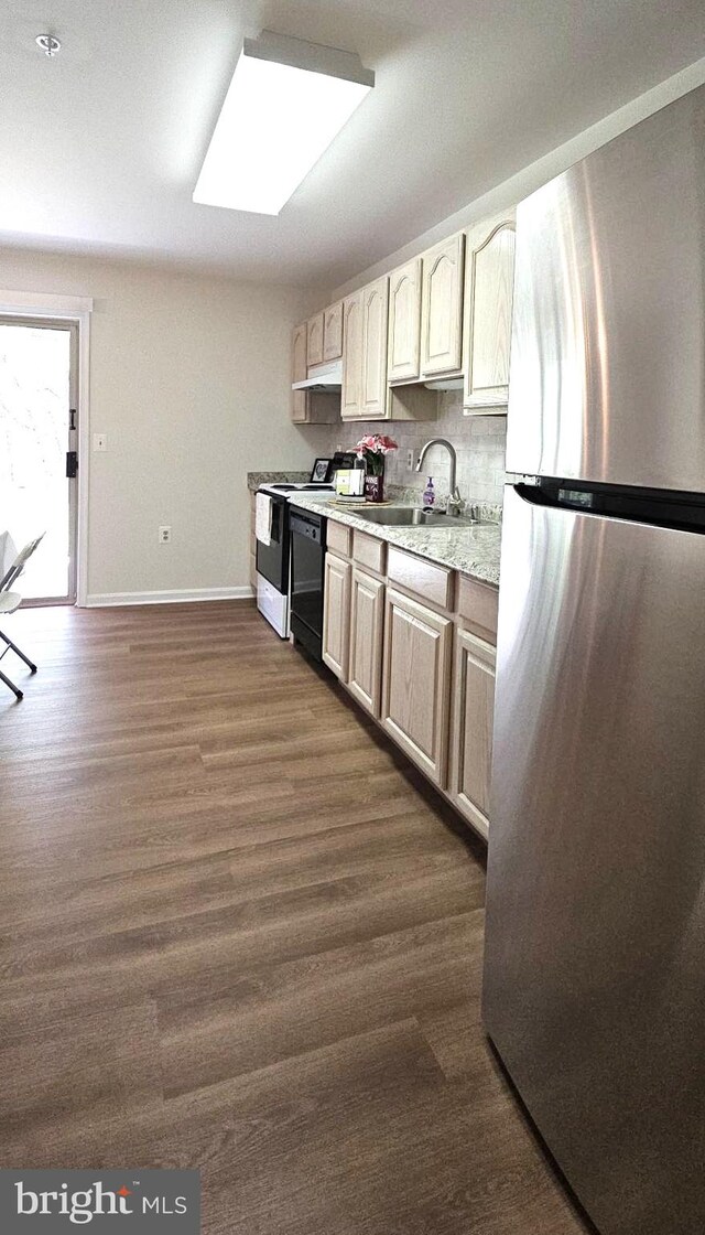kitchen featuring range with electric stovetop, a sink, baseboards, light countertops, and freestanding refrigerator