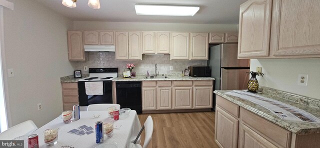 kitchen with a sink, light brown cabinets, light wood-type flooring, under cabinet range hood, and black appliances