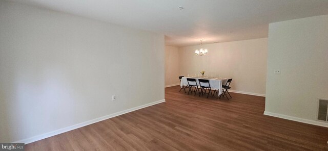 unfurnished dining area featuring baseboards, wood finished floors, and a chandelier