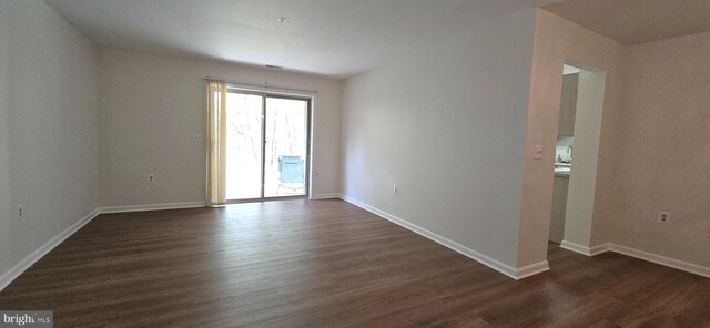 spare room featuring baseboards and dark wood-style flooring