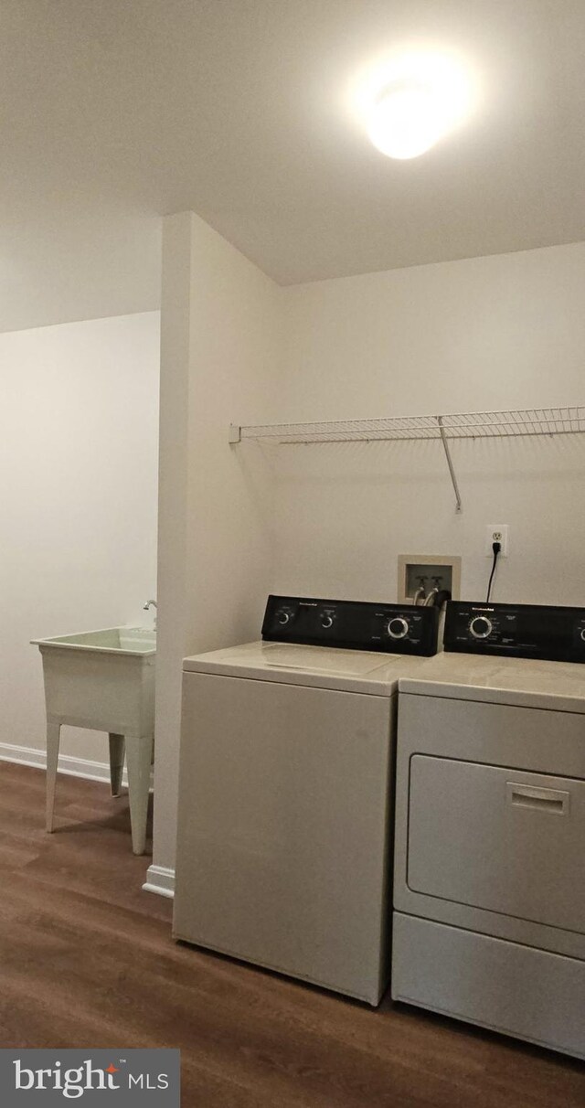 washroom featuring laundry area, baseboards, dark wood-type flooring, and washing machine and clothes dryer