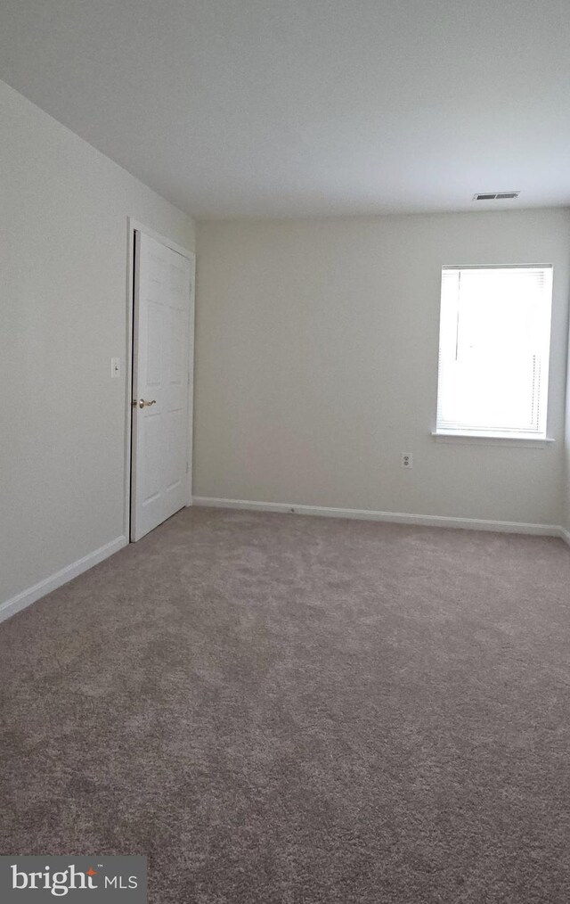 carpeted spare room with baseboards and visible vents