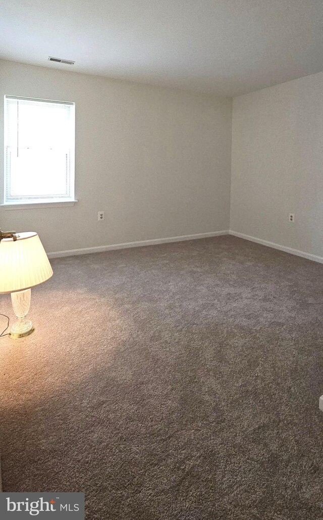 carpeted empty room featuring baseboards and visible vents