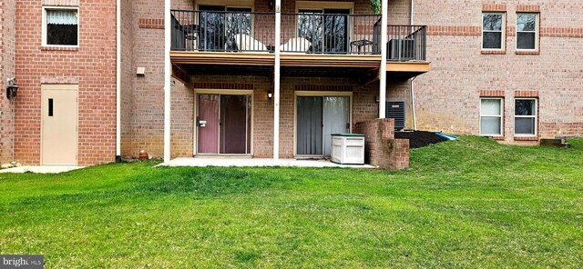 back of property with a lawn, brick siding, and a balcony