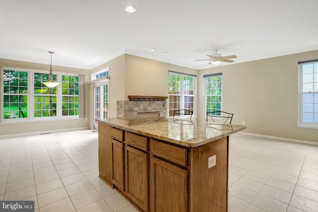 kitchen with brown cabinetry, baseboards, light tile patterned flooring, and a healthy amount of sunlight