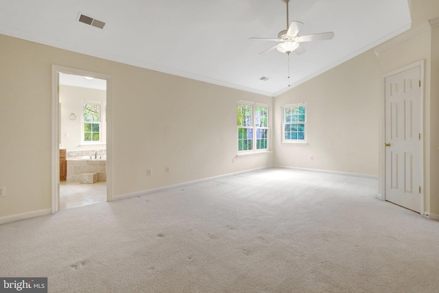 carpeted spare room featuring crown molding, visible vents, plenty of natural light, and vaulted ceiling